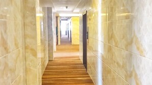 A corridor with marble walls and a wooden floor, leading to a door at the end. - Rongxian Wanxuan Hotel (Rong County)