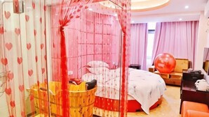 A hotel room with a bed, a wooden tub, a desk, and a large red exercise ball. - Rongxian Wanxuan Hotel (Rong County)