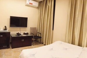 A hotel room with a bed, a desk, a chair, a television, and a window with curtains. - Rongxian Wanxuan Hotel (Rong County)
