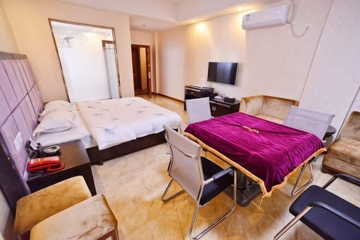 A hotel room with two beds, a desk, a chair, a TV, and a mirror.