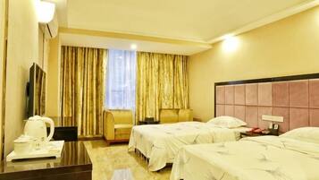 A hotel room with two beds, a desk with a kettle, a chair, a TV, and a window with curtains.