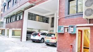A parking garage with two cars, a red brick building, and a covered area with a staircase. - Rongxian Wanxuan Hotel (Rong County)