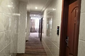 A hallway with marble walls, a wooden carpet, and a wooden door. - Rongxian Wanxuan Hotel (Rong County)