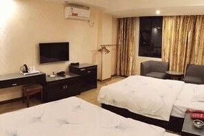 A hotel room with two beds, a desk with a TV, a chair, and a small table with a phone and a cup. - Rongxian Wanxuan Hotel (Rong County)