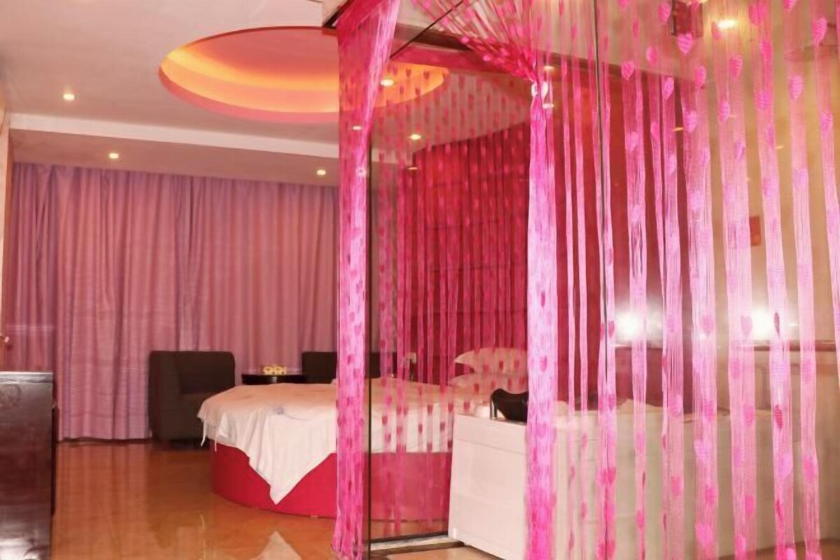 A bedroom with a canopy bed, a bedside table, and a chair.