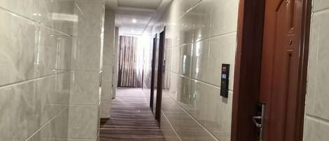A corridor with a wooden floor, white walls, and a door on the right.