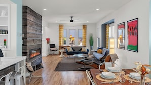 A modern living room with a fireplace, seating area, and dining space. - Beachside, Chefs Kitchen, High-End Everything (Sheboygan)