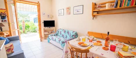 En matplats med ett bord dukat för två personer, en soffa och en tv i bakgrunden.