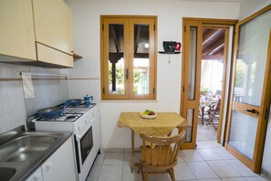 Una cocina con estufa, lavamanos y una mesa de comedor con sillas.