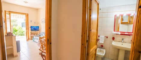 Un pasillo que conduce a una sala de estar con televisor, muebles de madera y vistas al exterior.