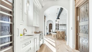 Eine moderne Küche mit weißen Schränken, einer zentralen Kochinsel und Blick in den Essbereich.