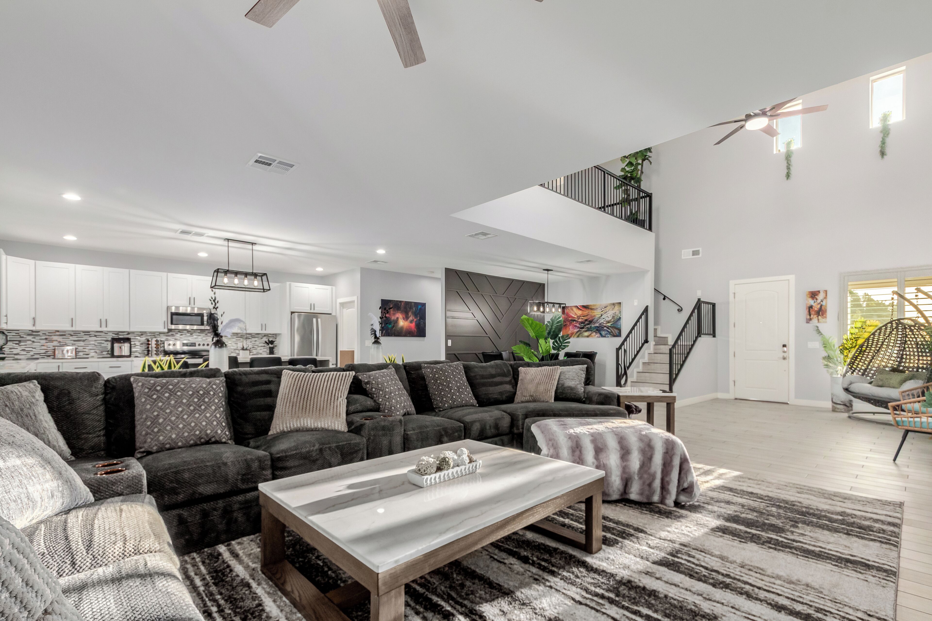 Un salón amplio con un sofá modular grande, una mesita de centro y una escalera que sube a un nivel superior.
