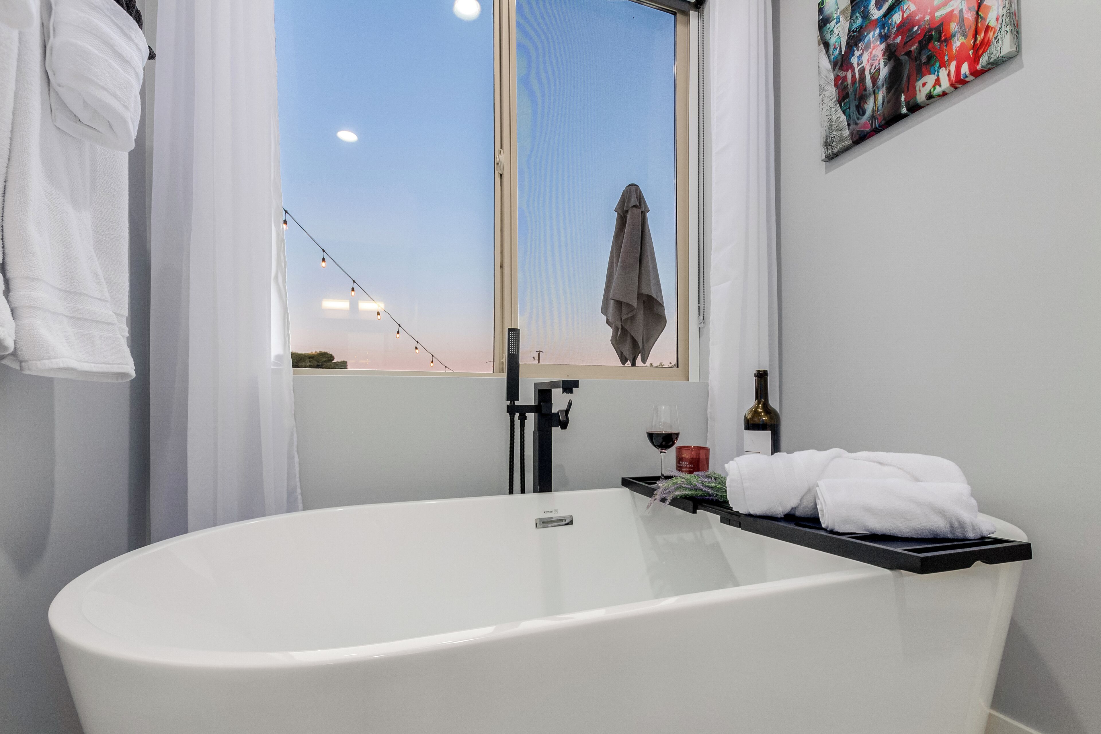 Ein modernes Badezimmer mit freistehender Badewanne, einem Fenster mit Aussicht und einem Handtuchhalter.