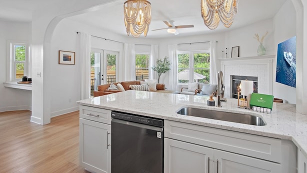 A modern kitchen with a large island, white cabinetry, and a dishwasher.