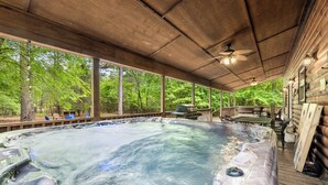 A hot tub under a wooden deck with a view of a forest.