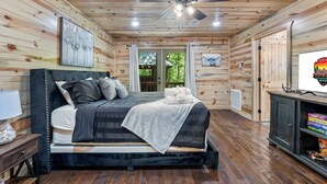 Une chambre dans une cabane en bois, avec un lit, un ventilateur de plafond et une bibliothèque.