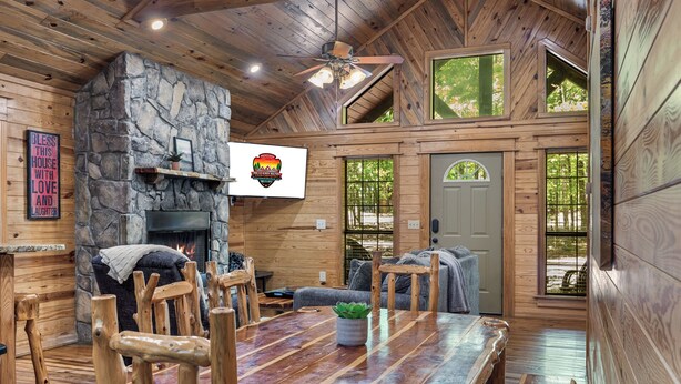 L’intérieur d’un chalet rustique, avec une cheminée en pierre, des meubles en bois et de grandes fenêtres.