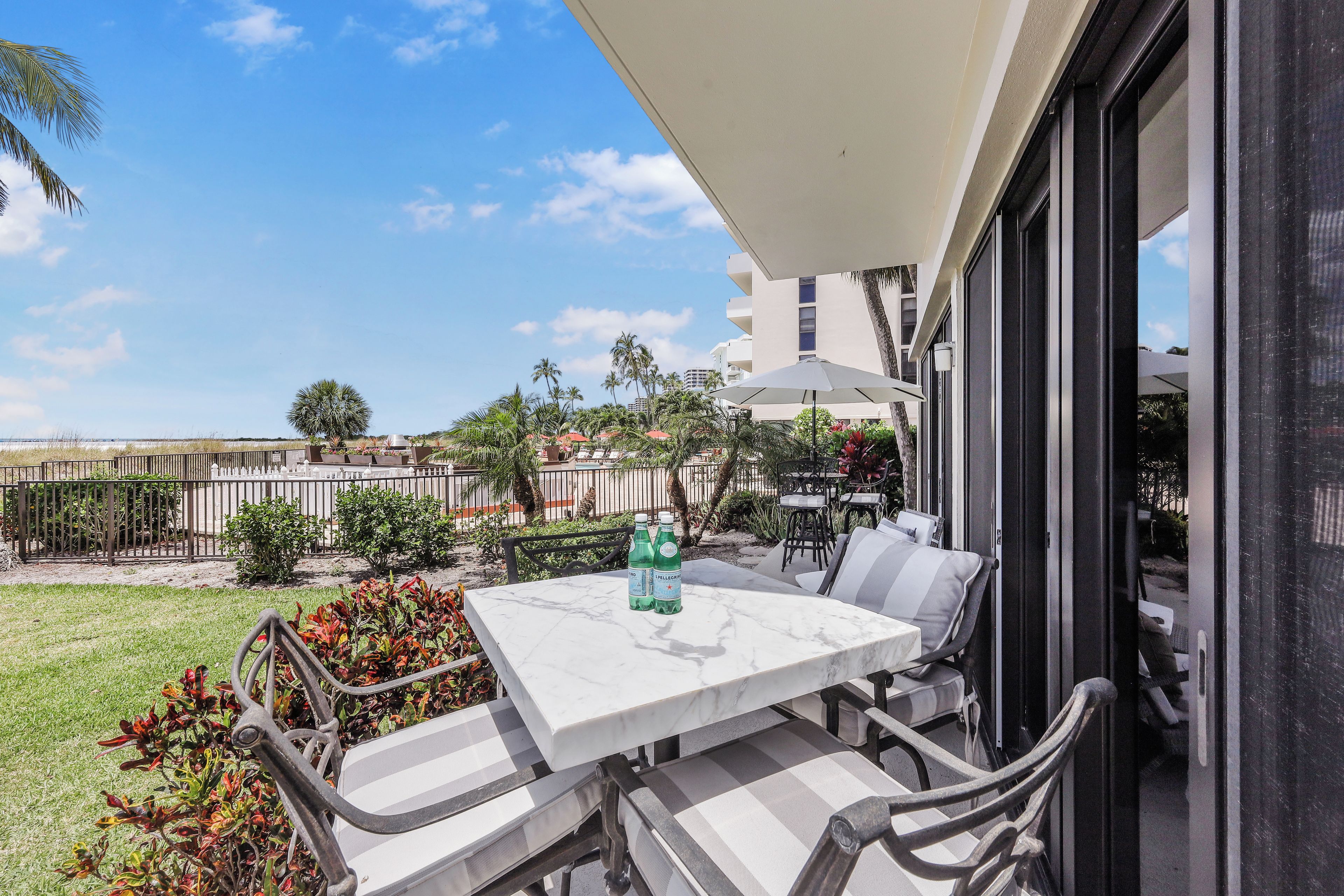 A balcony with a table and chairs, a view of the surrounding area, and a building in the background.