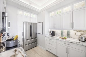 A modern kitchen with white cabinetry, stainless steel appliances, and a marble countertop. - Extremely Rare Walkout Unit | Steps From Beach (Marco Island)