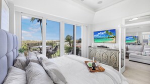Un'ampia camera da letto con un letto grande, una TV e un balcone vista spiaggia.