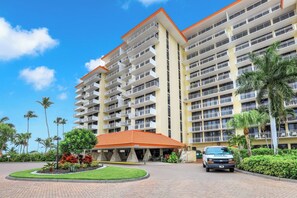 A multi-story hotel with a central courtyard, a covered entrance, and a vehicle parked in front. - Extremely Rare Walkout Unit | Steps From Beach (Marco Island)