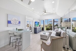 A spacious living area with a glass dining table, a sofa, and a television. - Extremely Rare Walkout Unit | Steps From Beach (Marco Island)