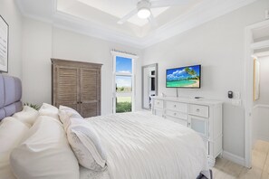 A bedroom with a bed, a dresser, a television, and a view of the outdoors. - Extremely Rare Walkout Unit | Steps From Beach (Marco Island)