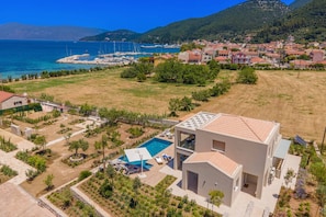 A modern house with a swimming pool, surrounded by a well-maintained garden and a view of the sea.