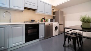 Uma cozinha moderna com armários brancos, eletrodomésticos de aço inoxidável, lava-louças e micro-ondas.