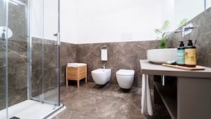 A modern bathroom with a glass shower enclosure, a sink with toiletries, and a toilet. - Planeta Palace - Junior Apartment (Palermo)