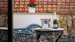 A table with a bottle of wine and a glass, set on a decorative table with intricate metalwork. - Planeta Palace - Apartment with terrace (Palermo)