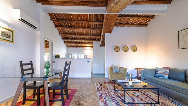 A modern living room with a glass dining table, wooden chairs, a colorful striped rug, a sofa, and a coffee table. - Planeta Palace - Apartment with terrace (Palermo)