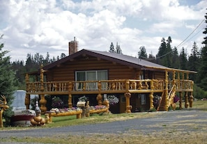 A log cabin with a balcony, surrounded by a landscaped garden.
