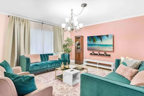 A living room with teal sofas, a white coffee table, and a pink wall.
