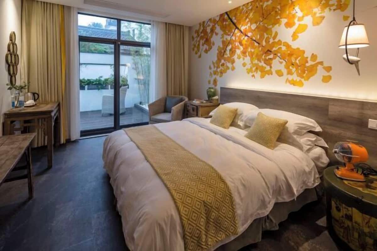 A hotel room with a large bed, a desk, a chair, and a view of the outdoors.
