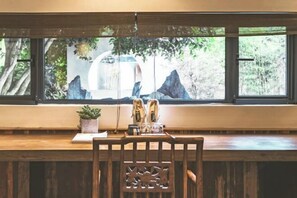 A wooden desk with a view of a waterfall and mountains through large windows. - Youjian Shibashe Inn (Suzhou)