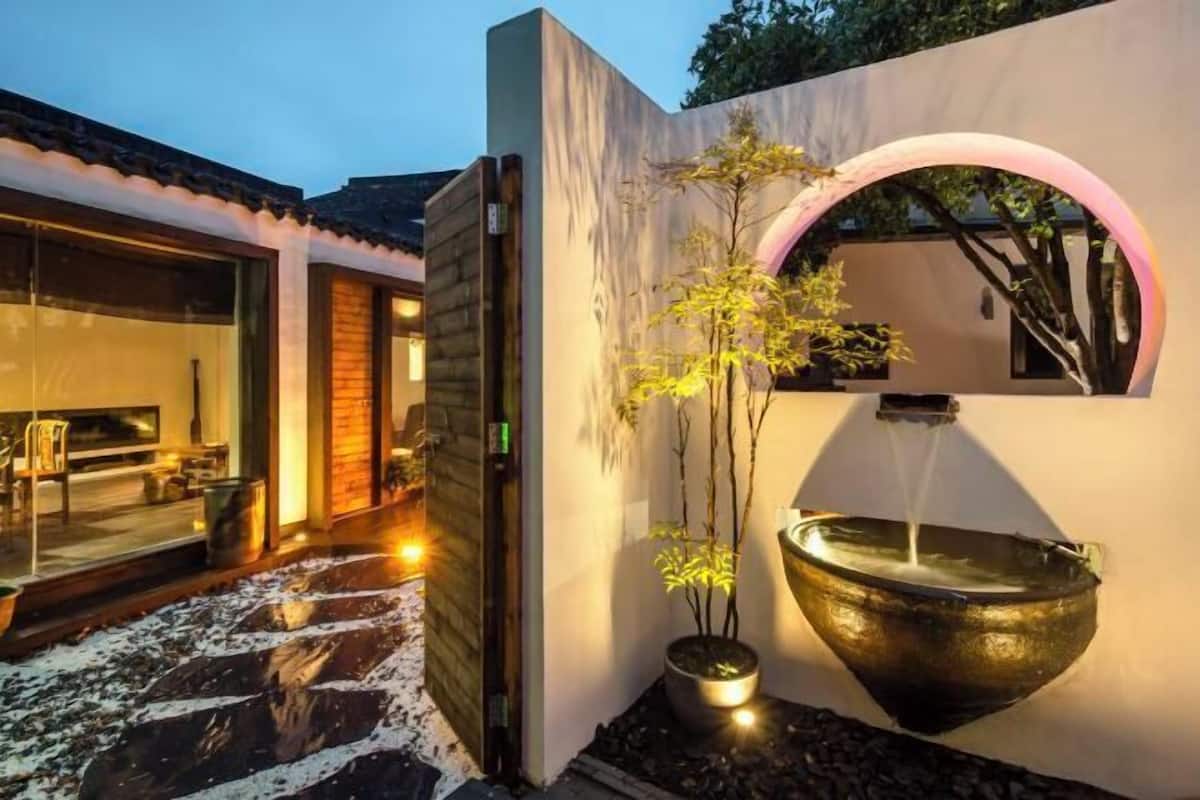 A modern building with a glass entrance, a potted plant, and a water feature.