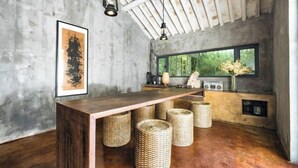Een landelijke keuken met een houten bar, gevlochten manden en een groot raam met uitzicht op groen.