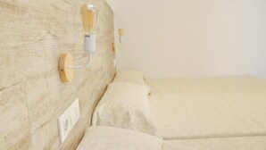 Un lit avec une tête de lit en bois, un luminaire fixé au mur et une prise de courant.