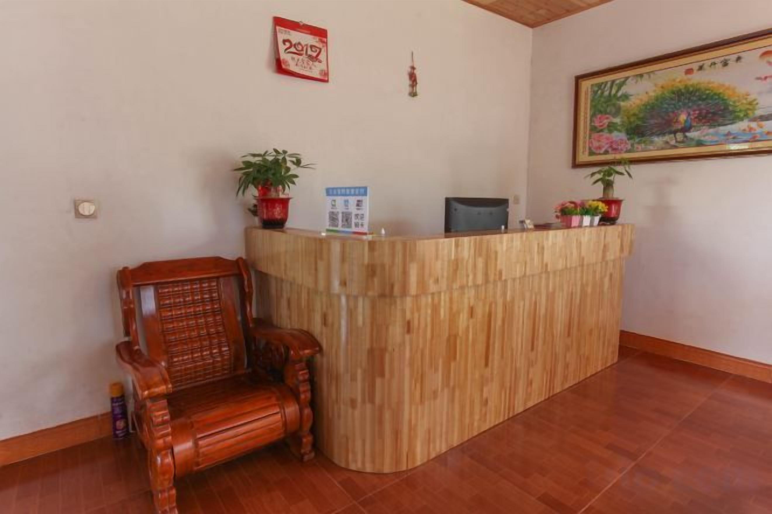 A reception desk with a wooden finish, a wooden chair, and a potted plant.
