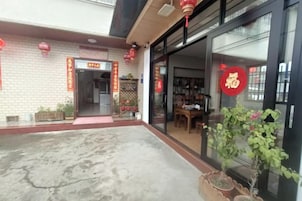 Fachada con un letrero rojo, puerta de vidrio y plantas en macetas.
