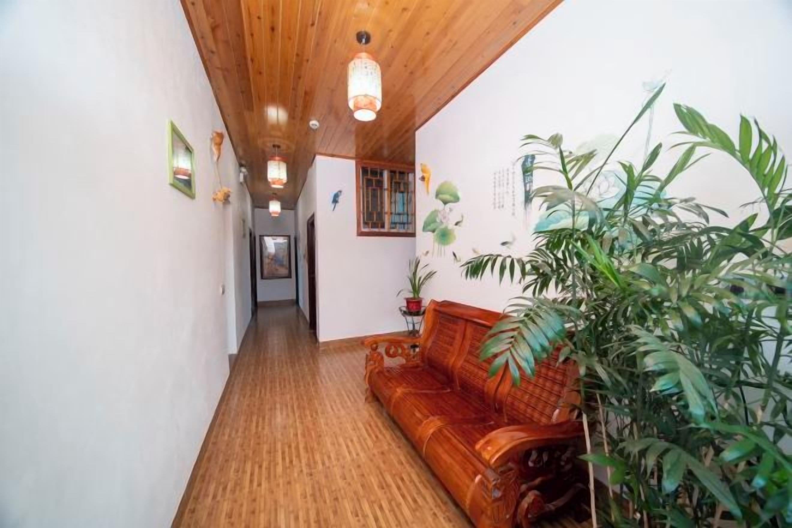 Un pasillo con suelo de madera, un banco de madera y una planta en maceta.