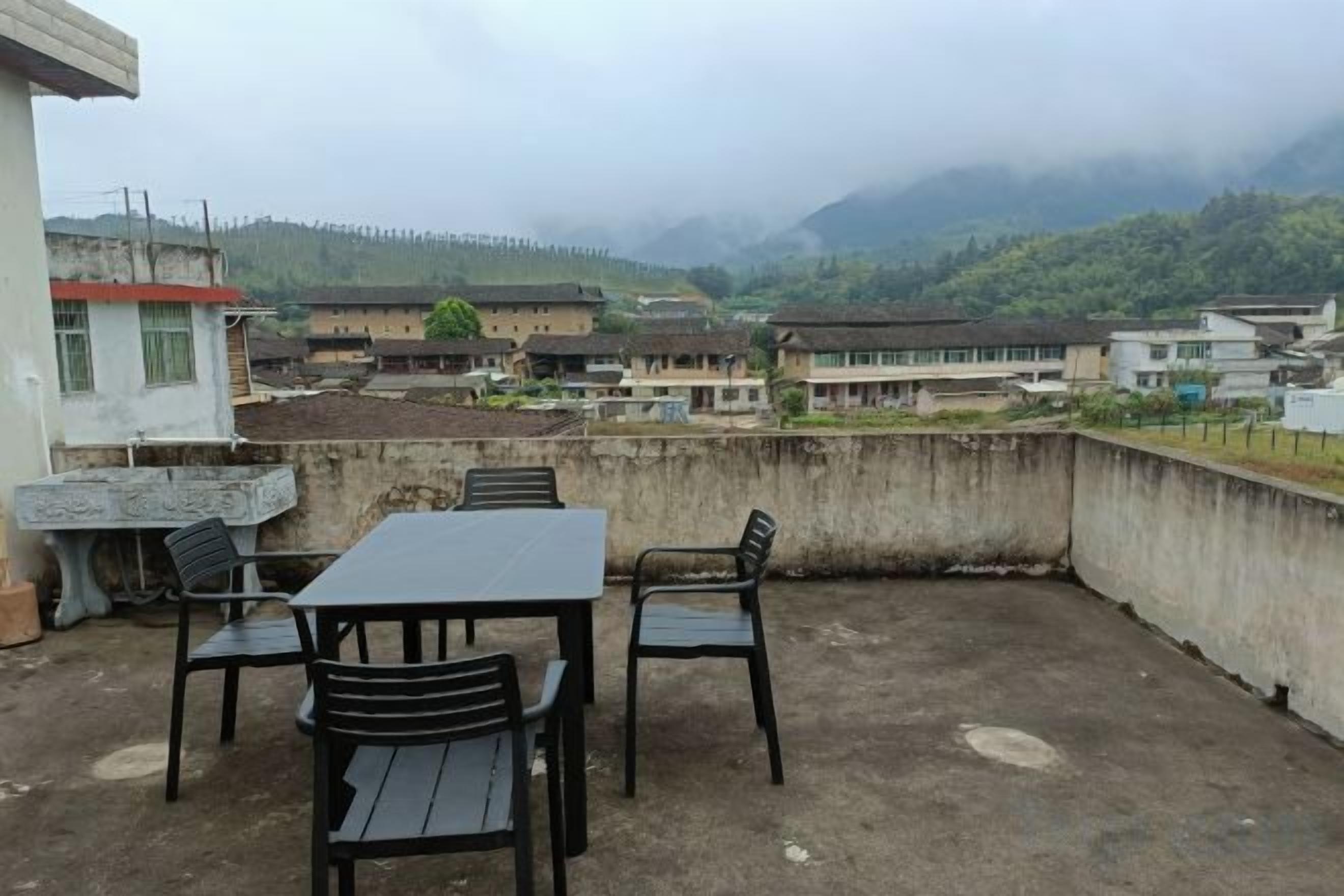 Una terraza en la azotea con una mesa y sillas, con vistas a un pueblo y montañas.