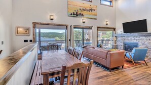 A spacious living area with a wooden dining table, a leather sofa, and a stone fireplace. - Hillside Lodge of the Black Hills (Sturgis)