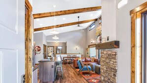 A spacious living area with a kitchen island, wooden flooring, and a stone fireplace. - Hillside Lodge of the Black Hills (Sturgis)