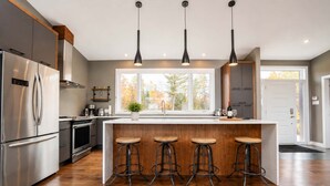 A modern kitchen with a central island, stainless steel appliances, and bar stools.