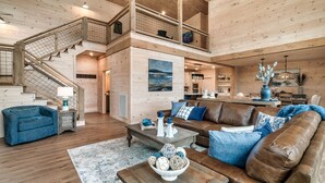 Un salón espacioso con una escalera de madera, un sofá grande y una zona de comedor.