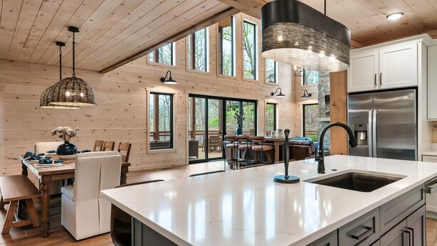 Una cocina amplia con una isla grande, techo de madera y ventanas panorámicas.