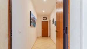 A hallway with tiled flooring, wooden doors, and framed pictures on the walls. - Cloud Swing Room 1 by Wonderful Italy (Bari)