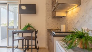 A modern kitchen with a built-in stove, a flat-screen TV mounted on the wall, and a dining area with a table and chairs. - Cloud Swing Room 2 by Wonderful Italy (Bari)